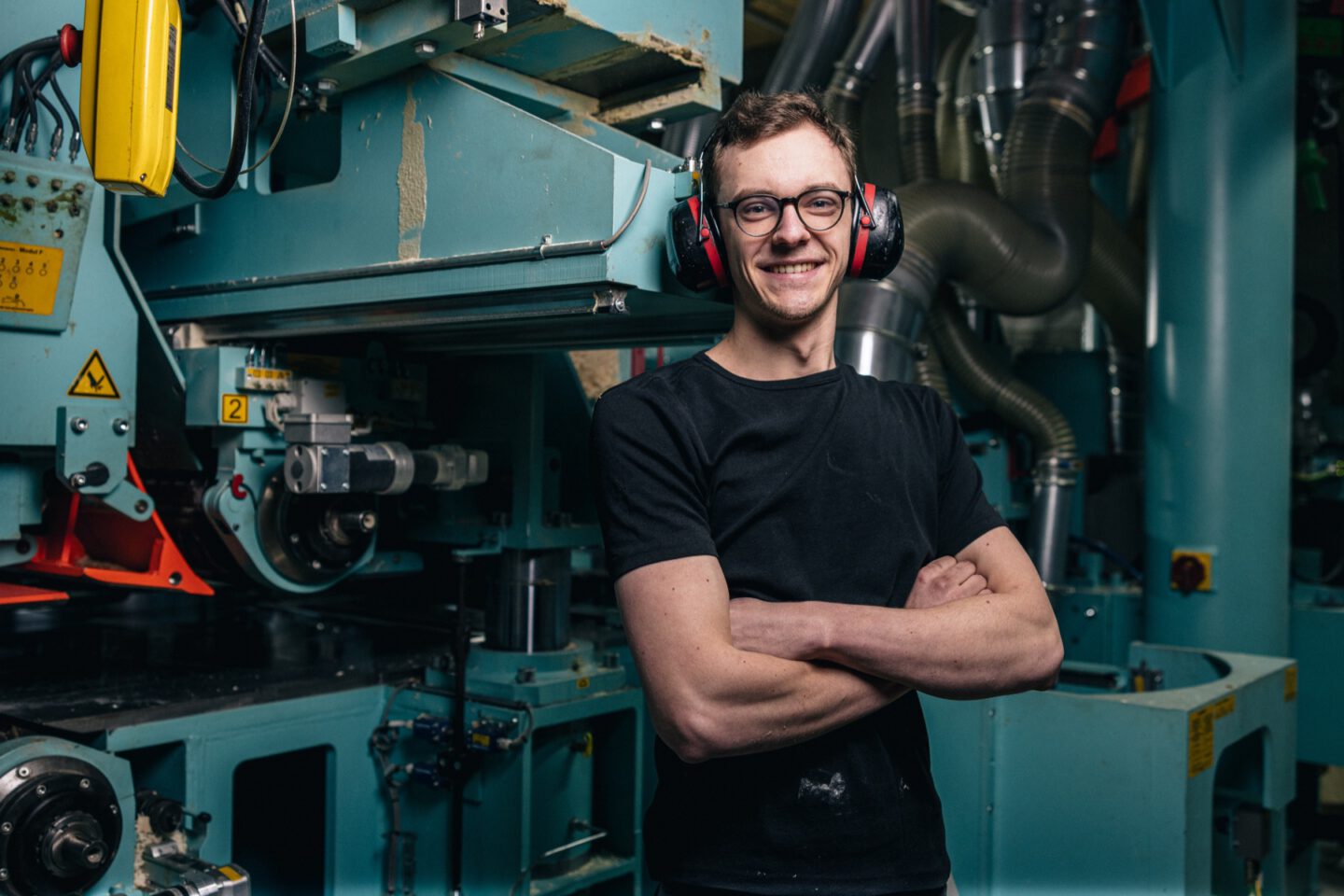 Auszubildender mit Gehörschutz vor einer Produktionsanlage bei Vente-Holz